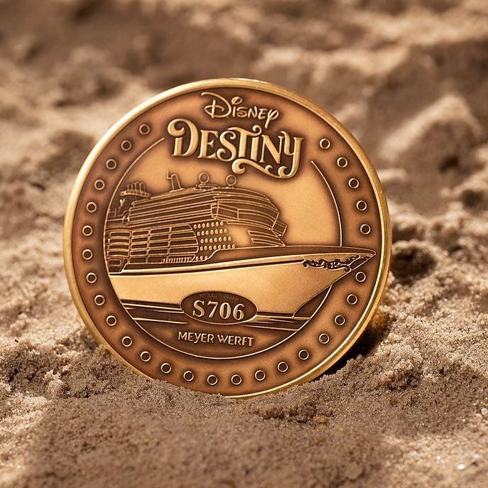 a disney destiny coin is laying in the sand