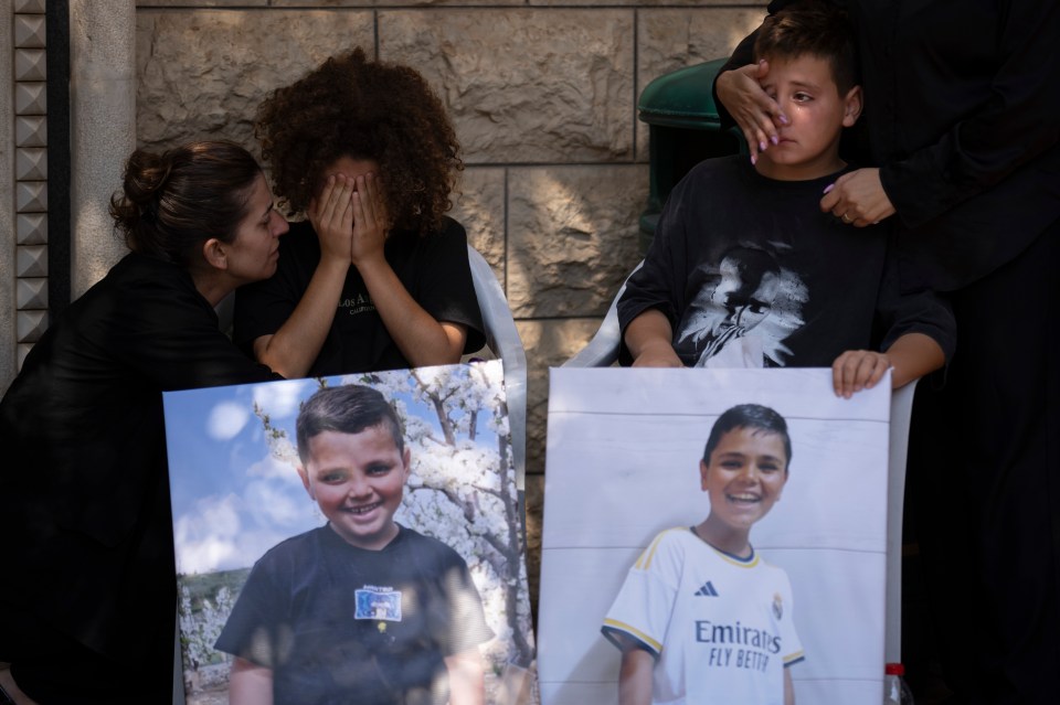 Mourners from victims' families weep during the funeral for two children