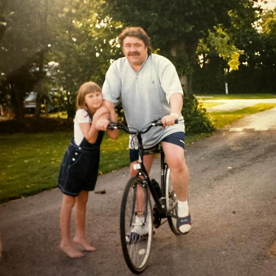 a man is riding a bike with a little girl on his shoulders