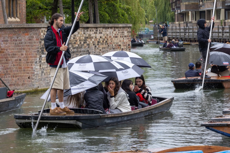 Tourisits huddle underneath umbrellas as the rain arrived in Cambridge yesterday