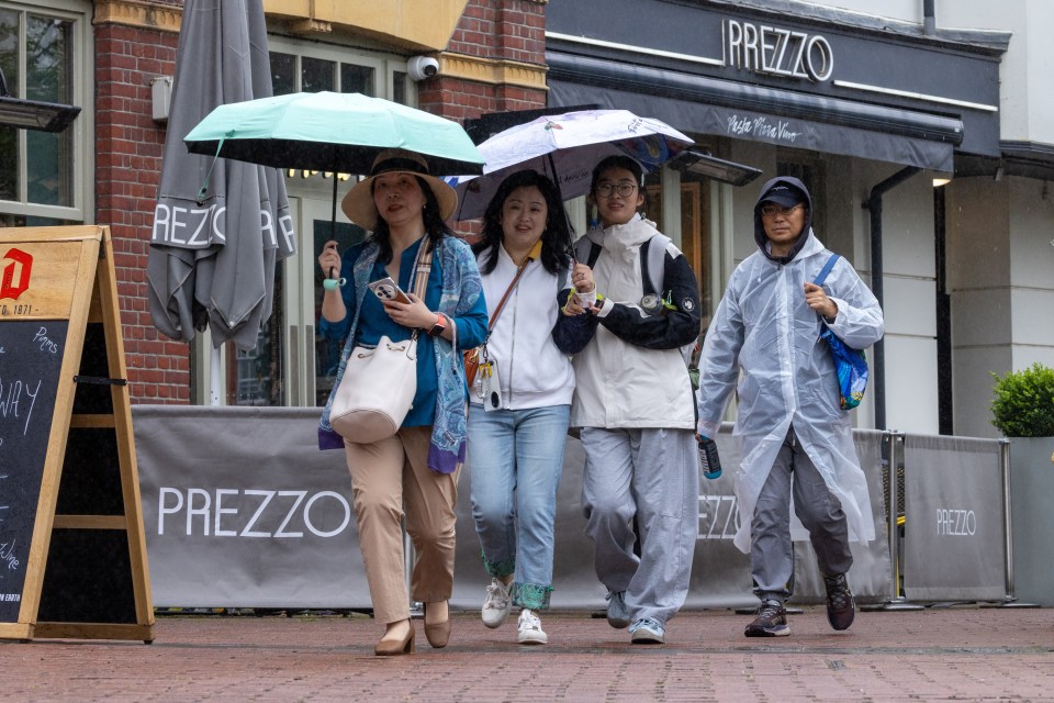 Shoppers hold umbrellas in Cambridge on Tuesday