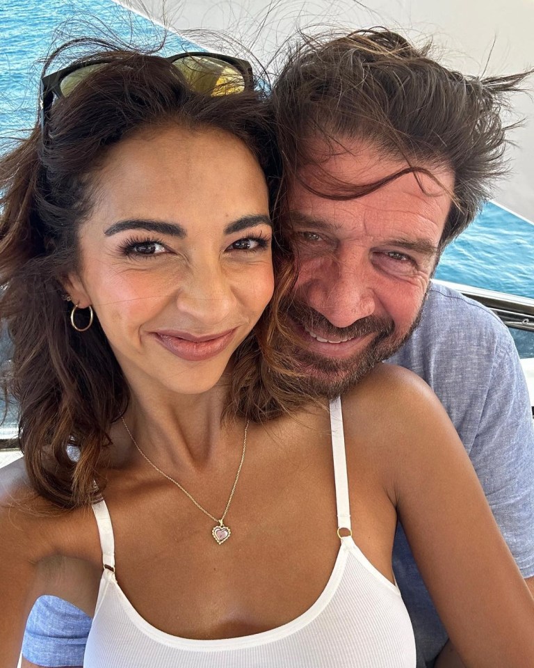 a man and a woman are posing for a picture and the woman is wearing a heart necklace