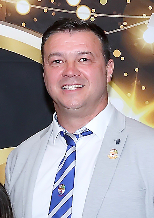 a man in a suit and tie with a badge on his jacket