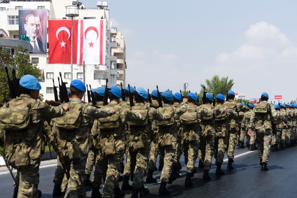 a group of soldiers marching down a street in front of a flag