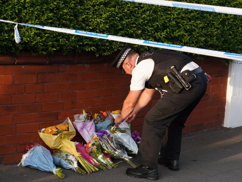 A cop lays flowers at the scene