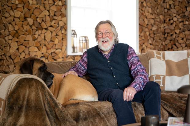 a man sits on a couch with a dog and a blanket with the letter h on it