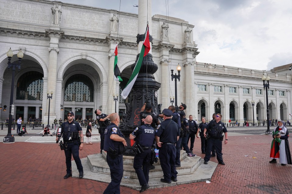 Police officers remove Palestine flags from one monument