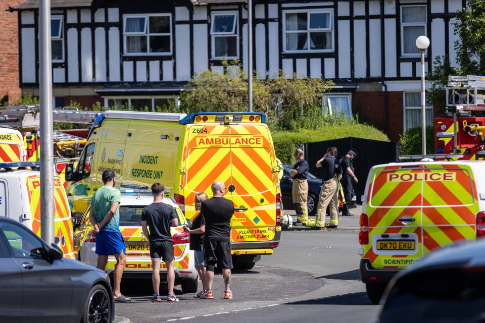 a group of people standing in front of an ambulance and a police van