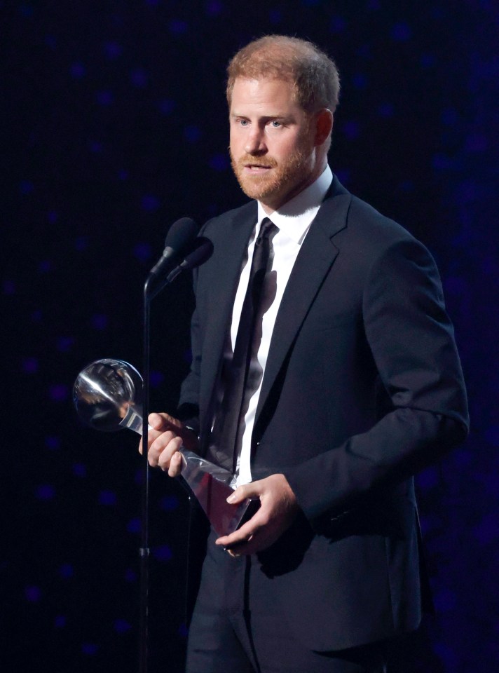 a man in a suit holds a trophy in front of a microphone