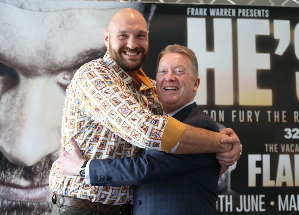 two men hugging in front of a poster that says frank warren presents