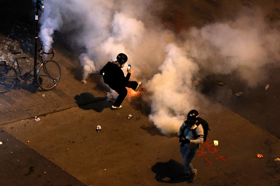 A demonstrator kicks back a tear gas canister as clashes continue in the French capital