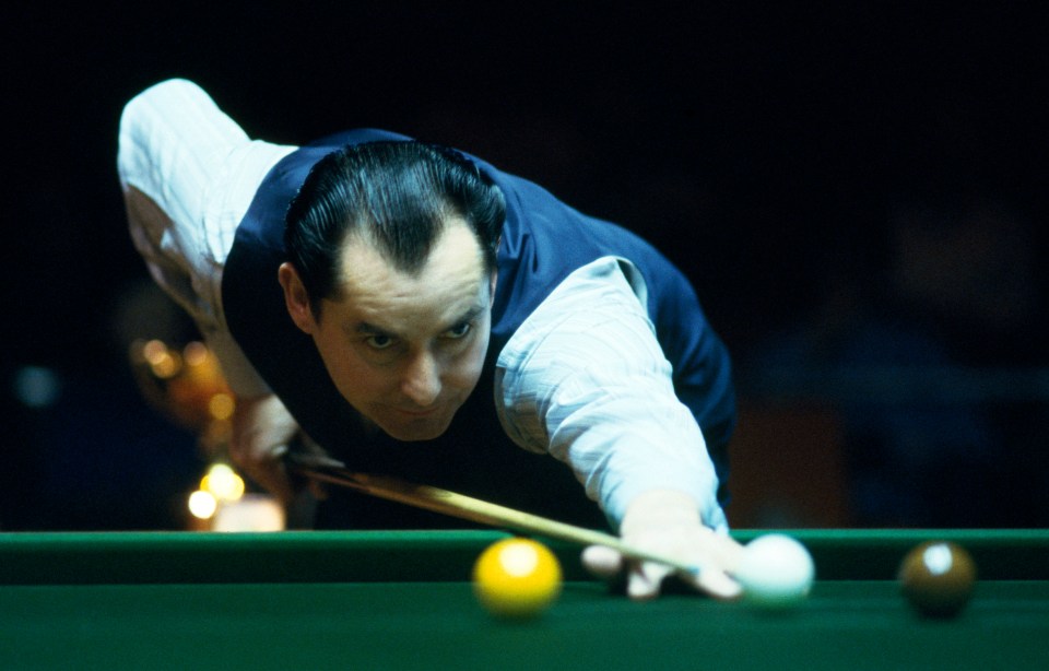 a man in a blue vest is playing pool