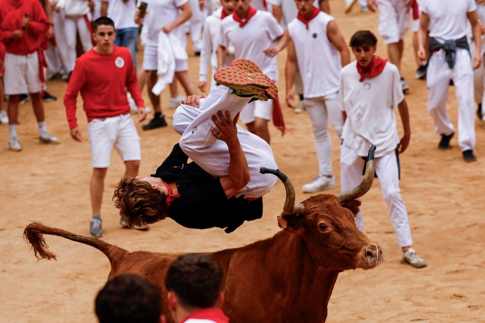 A reveller jumping over a wild cow at the San Fermin festival today