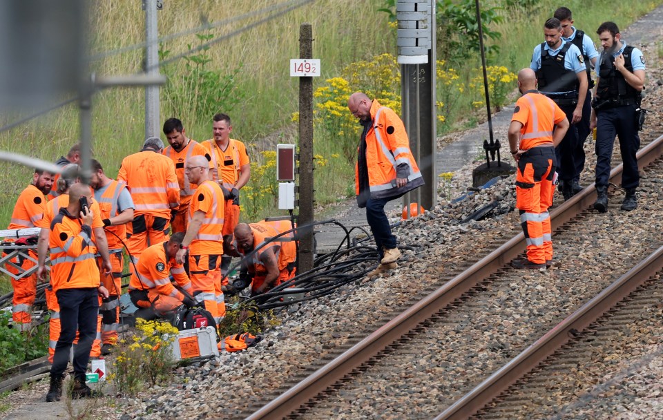 Railway employees and French gendarmes inspect the scene of an arson attack at Croiselles, France