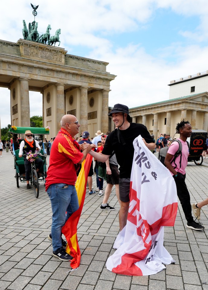 A Spain and England fan greet each other next to the Brandenburg Gate in Berlin