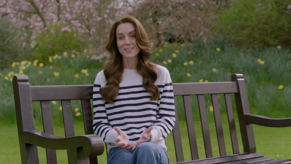 a woman in a striped sweater sits on a park bench