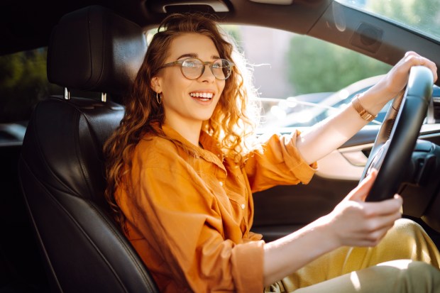 a woman wearing glasses is smiling while driving a car