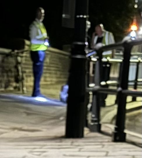 a group of people are standing on a sidewalk at night .