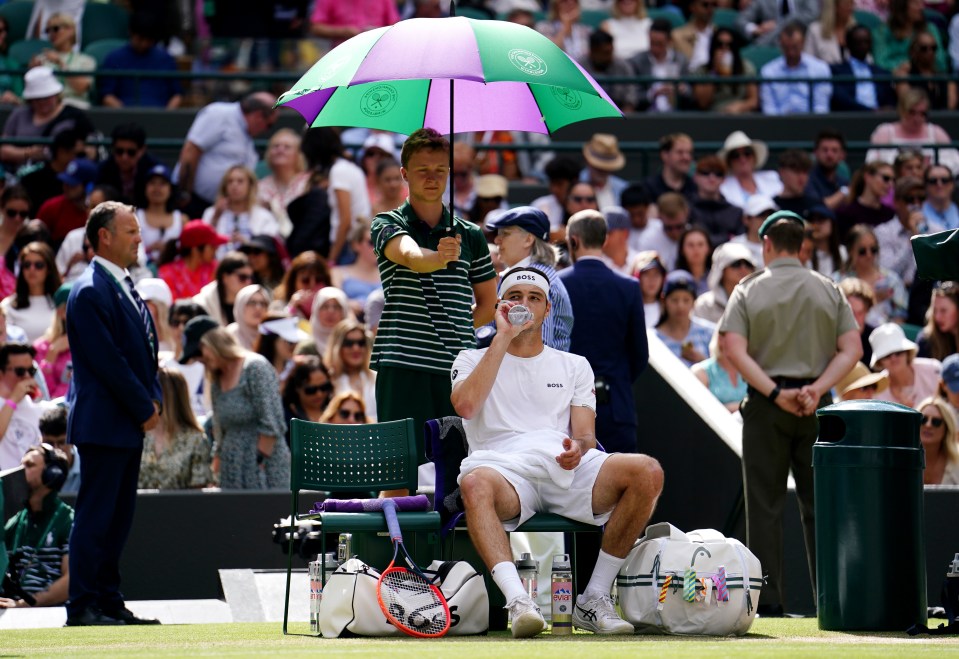 The American sipped his water under the shade of an umbrella during the break