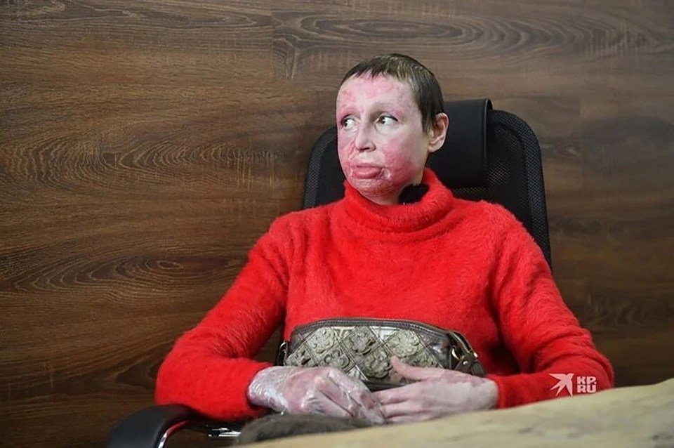 a woman wearing a red sweater is sitting in a chair with a purse in her hand