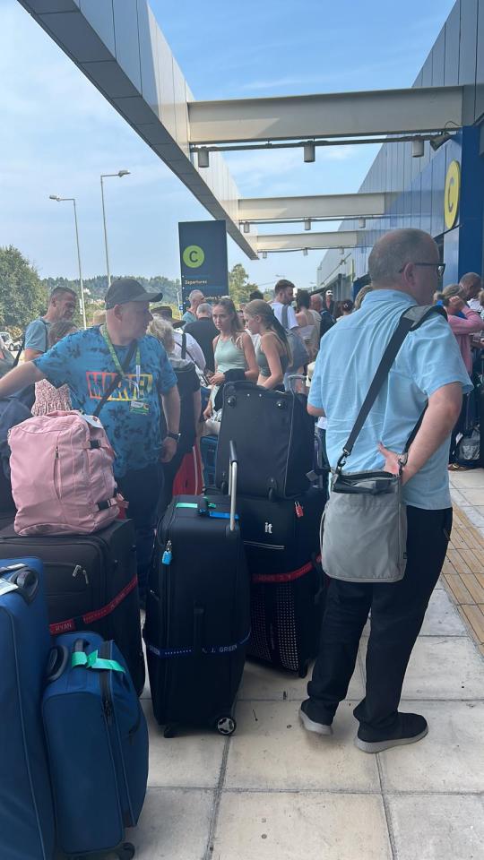 Customers are seen waiting outside the airport following the IT glitch