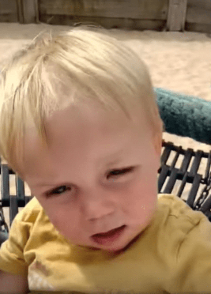 a young boy with blonde hair and a yellow shirt is sitting on a swing .