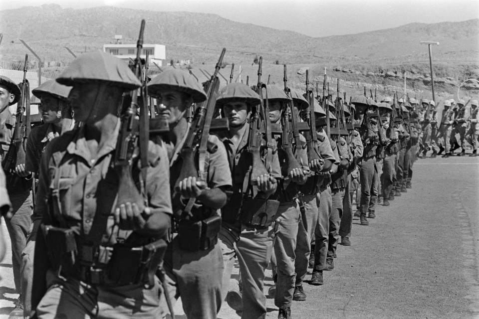 a black and white photo of soldiers marching in a line