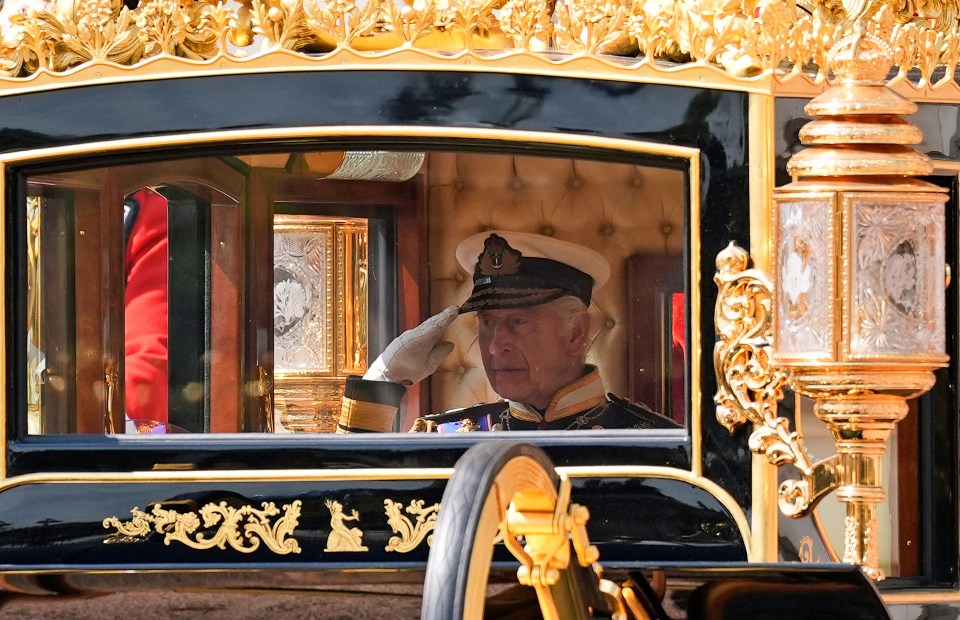 Britainâs King Charles III salutes as he travels with Britainâs Queen Camilla