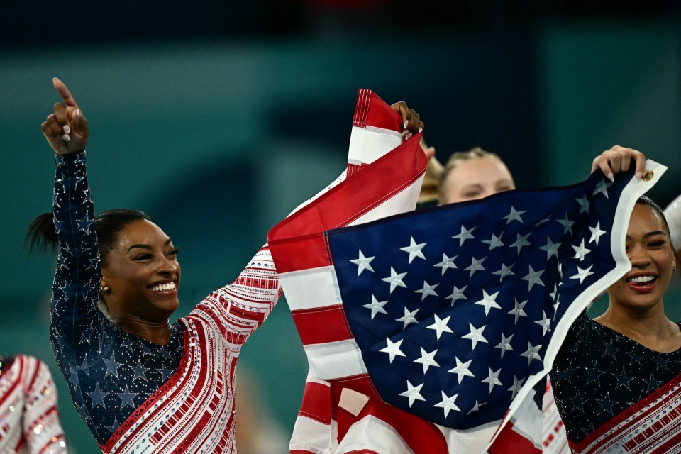 a woman in a blue and red outfit is holding an american flag