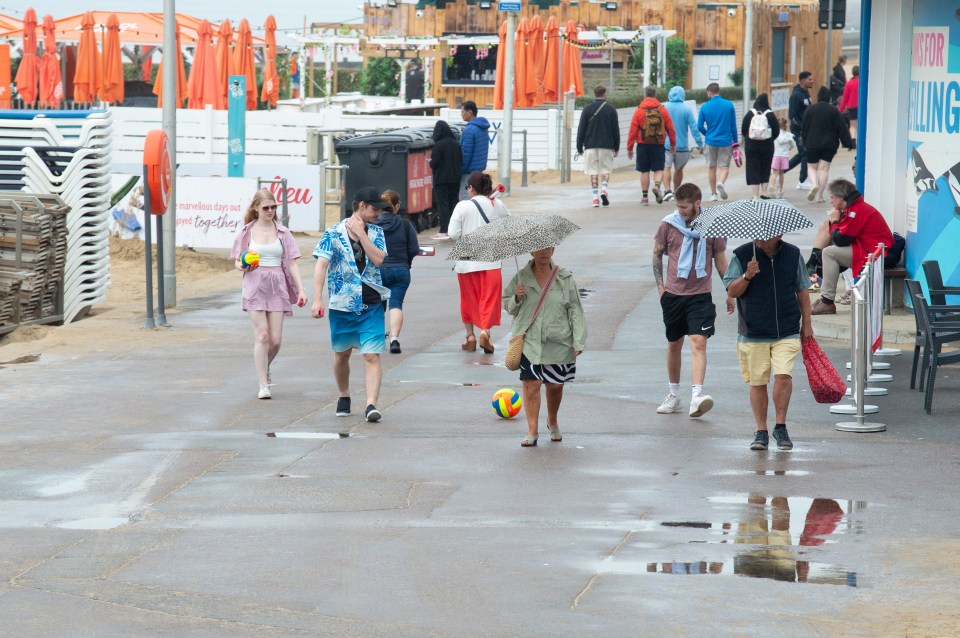 Rain will hit parts of the UK today (beach-goers in Bournemouth on Sunday)