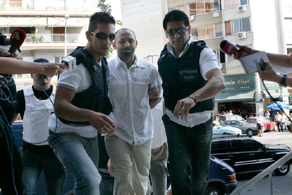 a man in a white shirt is being escorted by a man in a black vest with the word police on it