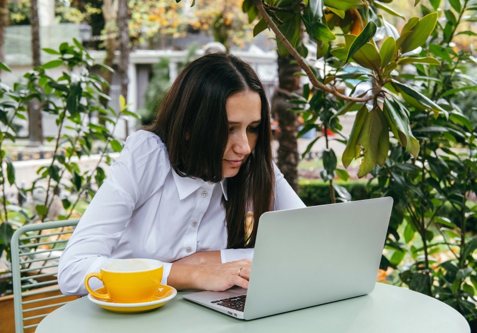 a woman sits at a table with a cup of coffee and a laptop