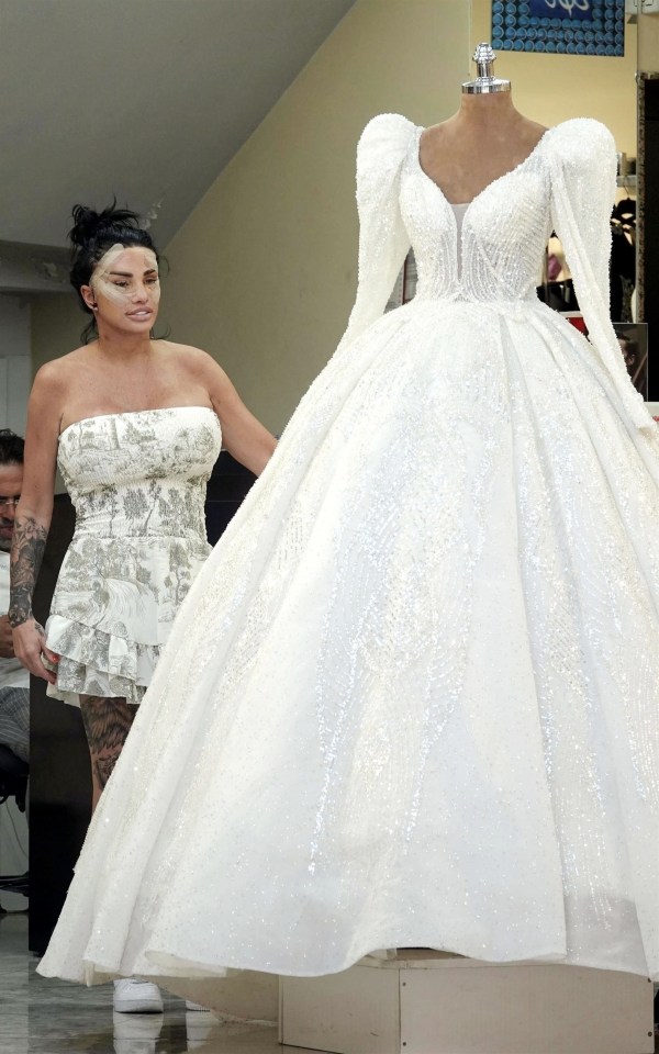 a woman in a white wedding dress stands next to a mannequin