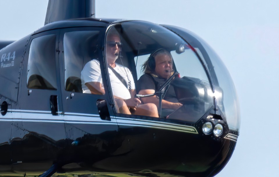 two people are sitting in a helicopter with the letters r44 on the side