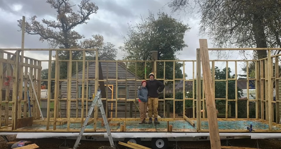 a man and a woman standing in front of a building under construction