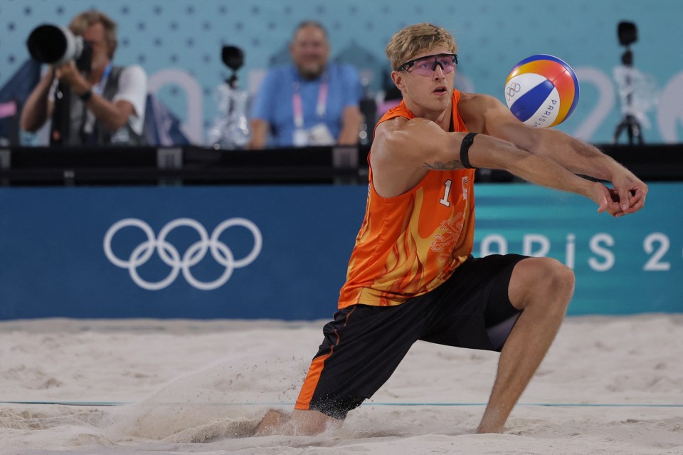 a man playing volleyball in front of the olympic rings