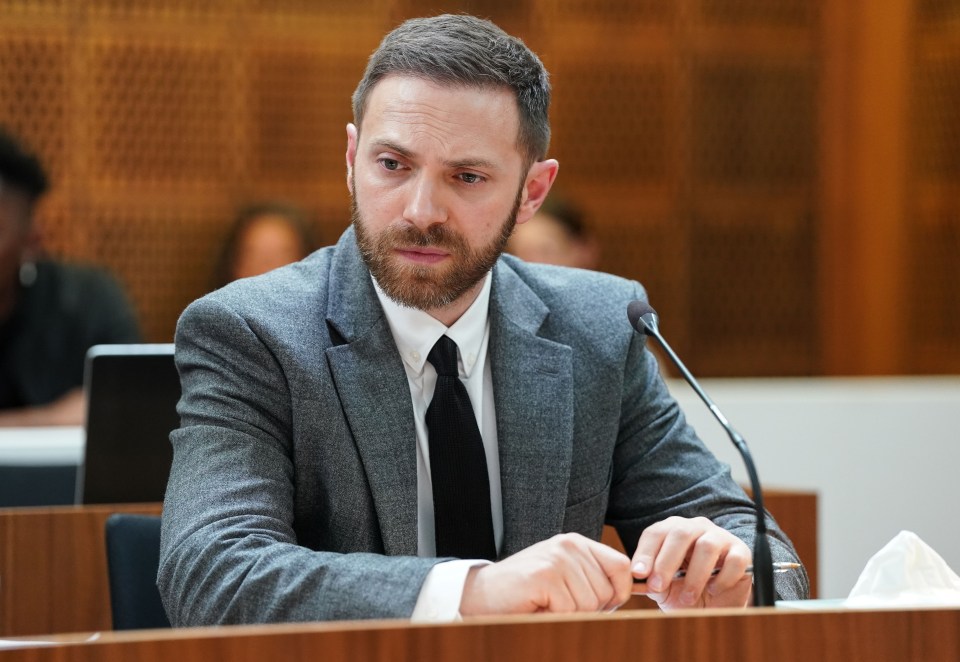 a man in a suit and tie sits in front of a microphone