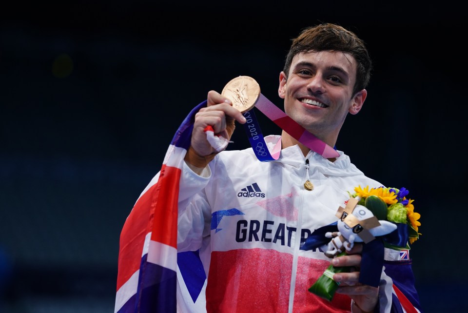 a man wearing an adidas jacket is holding a gold medal