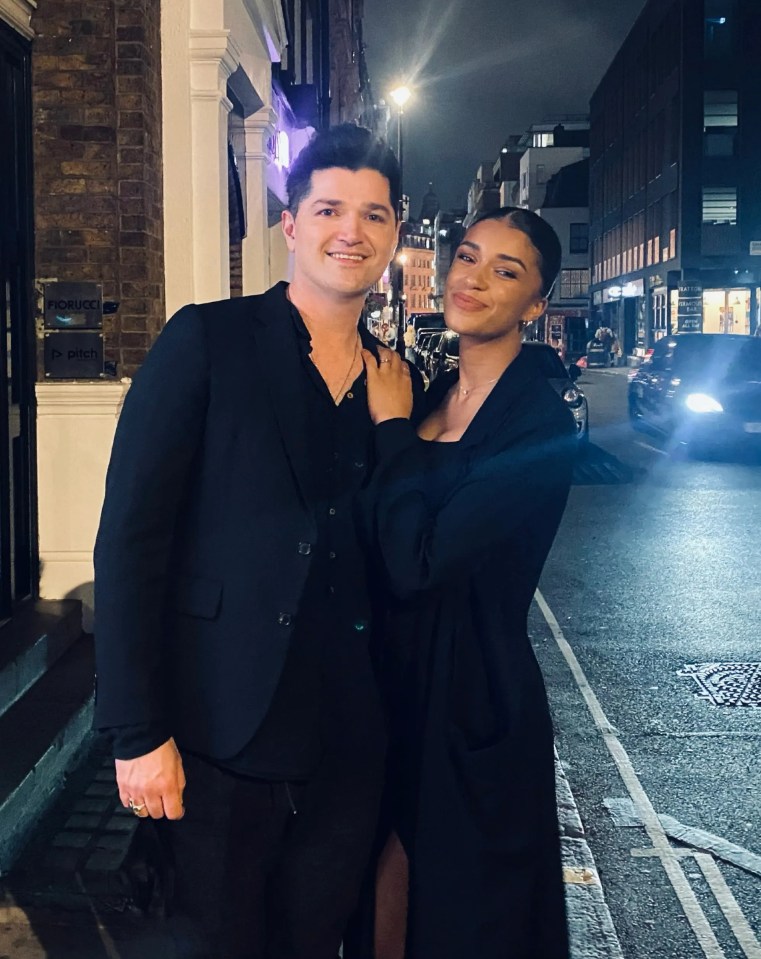 a man and a woman are posing for a picture in front of a building that says pitch