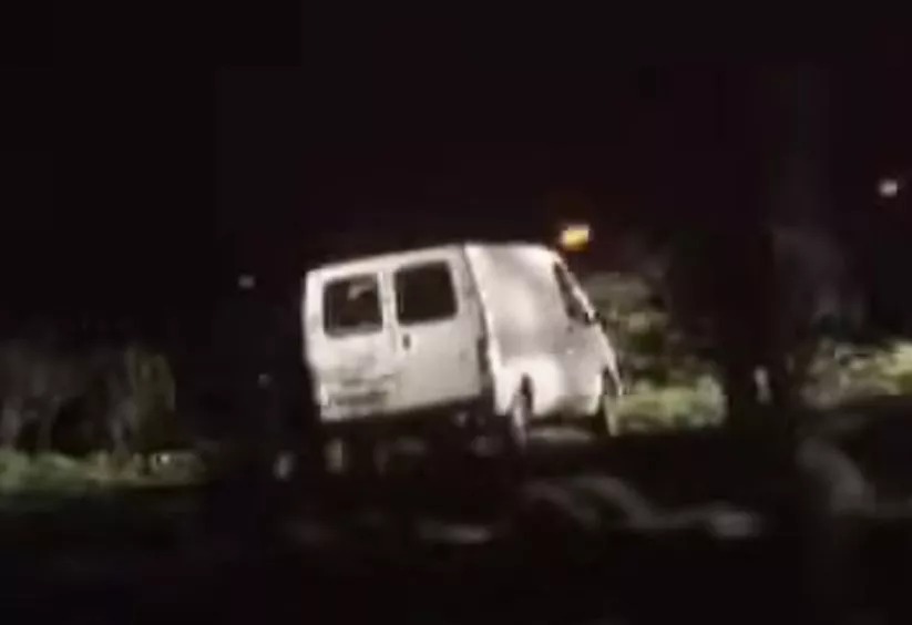 a white van is parked on the side of the road at night .