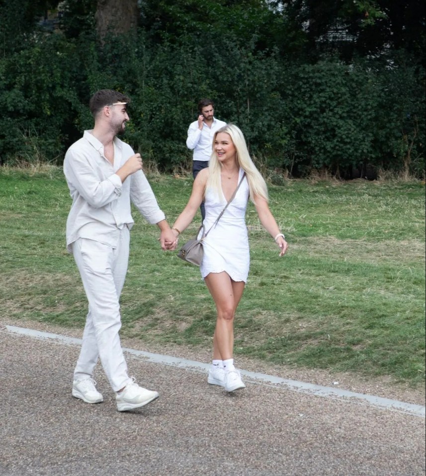 a man and a woman are walking down a sidewalk holding hands