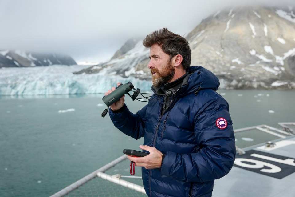 Aldo Kane looks out at icy water from the bow of OceanXplorer. (National Geographic/Mario Tadinac)