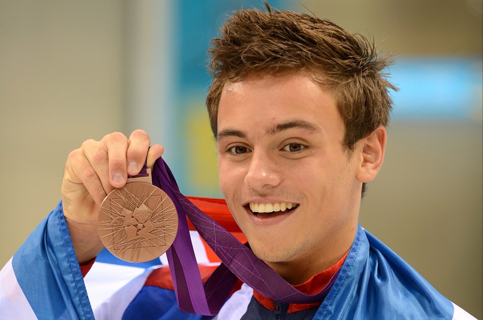 a young man is holding a bronze medal around his neck