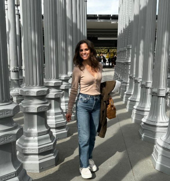 a woman stands in a maze of white columns