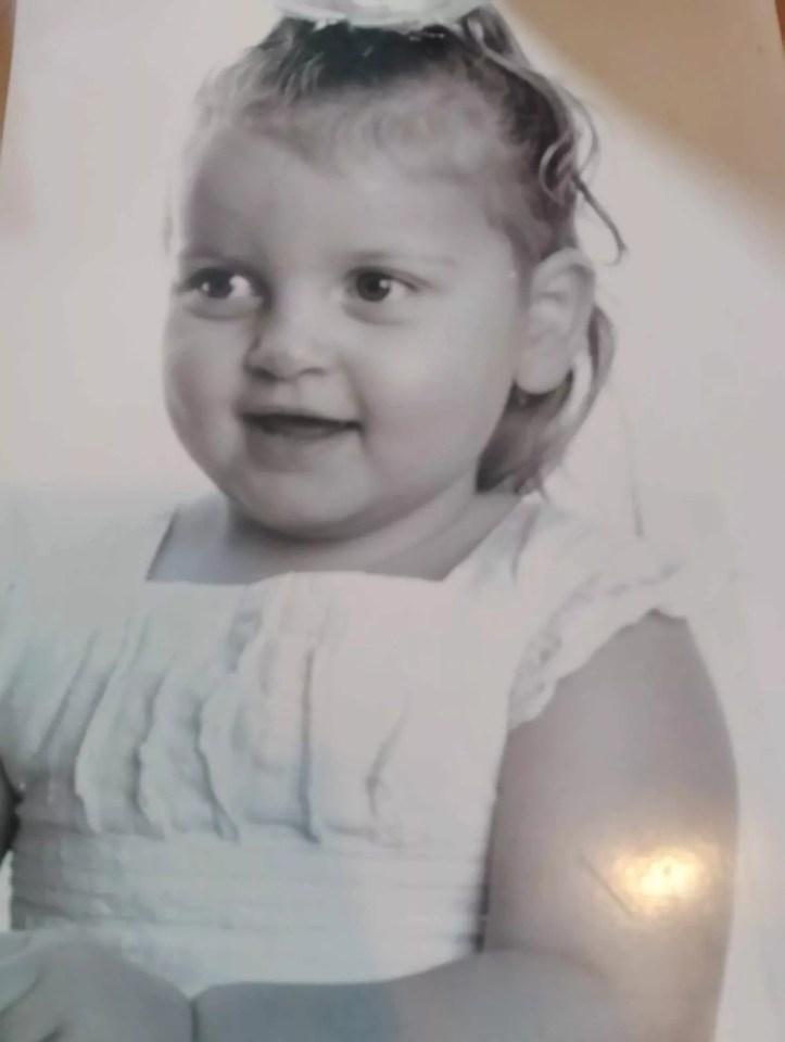 a black and white photo of a little girl in a white dress