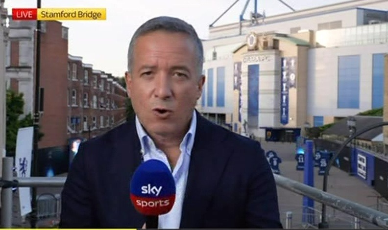 a man with a microphone in front of a screen that says sky sports