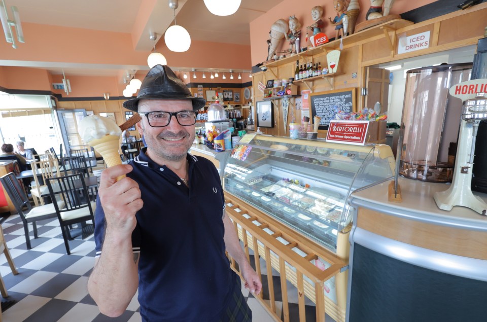 a man holding an ice cream cone in front of a sign that says iced drinks