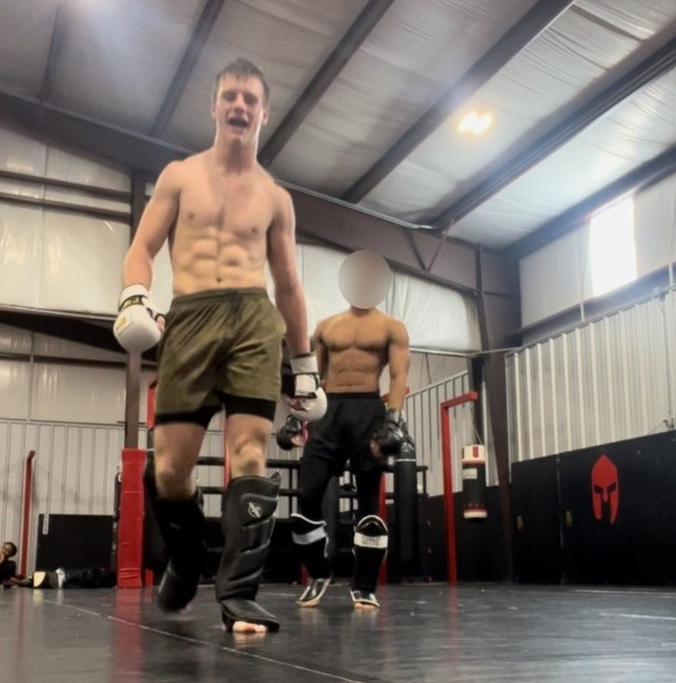 a man wearing boxing gloves stands in a gym