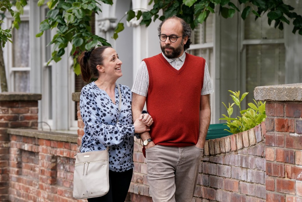 a man in a red vest stands next to a woman