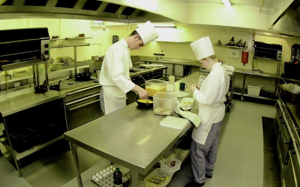 two chefs are preparing food in a commercial kitchen